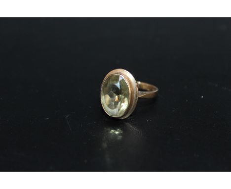 A HALLMARKED 9 CARAT GOLD DRESS RING, set with a pale olive green quartz style oval stone measuring an estimated 14mm by 10mm