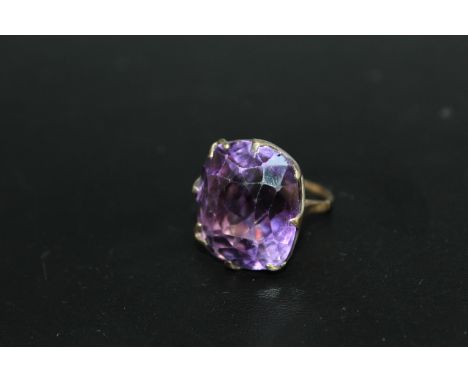 A VERY LARGE AMETHYST RING, the cushion cut style stone measures an approx 24 mm by 21 mm and is set in unmarked yellow and w