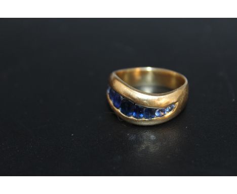 A HALLMARKED 18 CARAT GOLD SWIRL CHANNEL SET SAPPHIRE RING, set with 9 oval and circular sapphires, the end two on each side 