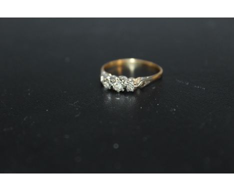 A THREE STONE DIAMOND RING, in an illusion setting with small diamond accents, marks extremely rubbed but thought to be 18ct,