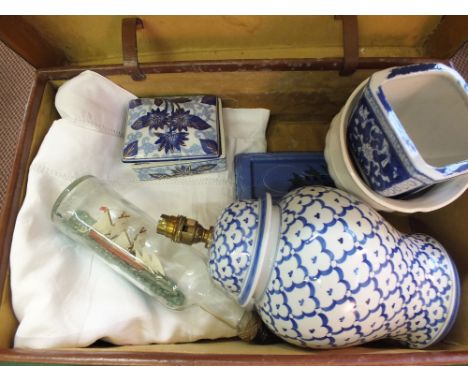 A leather case containing a table lamp, a ship in a bottle and linen, etc
