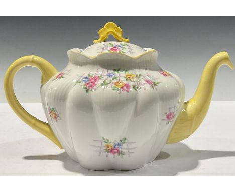 A Shelley teapot, decorated with flowers on a trellis, yellow handle and spout, 25cm long