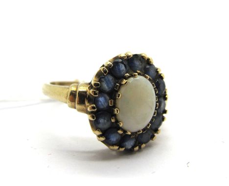 A 9ct Gold Opal and Sapphire Cluster Ring, oval claw set to the centre with a cabochon opal, within single border of circular