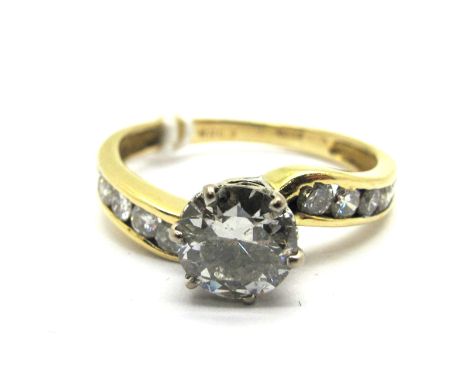 A Large Single Stone Diamond Ring, the brilliant cut stone six claw set between shaped channel set shoulders, stamped "750".