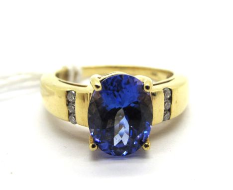 A Modern 18ct Gold Iliana Tanzanite and Diamond Set Dress Ring, oval four claw set to the centre between brilliant cut diamon