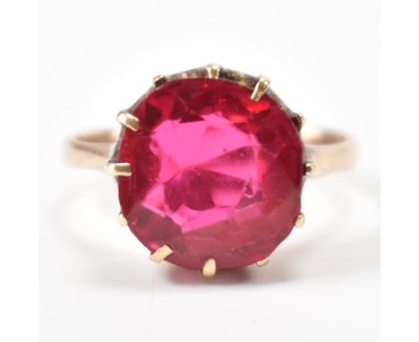 A hallmarked 9ct gold and synthetic ruby ring. The ring being set with a round cut ruby in a prong setting on a plain band. H