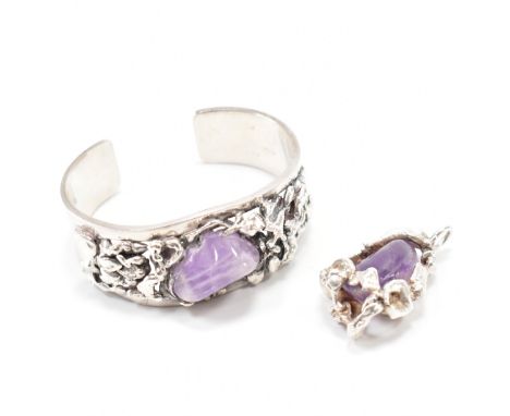 A silver and amethyst bracelet and pendant suite. The open bangle being set with a polished stone to the centre within a text