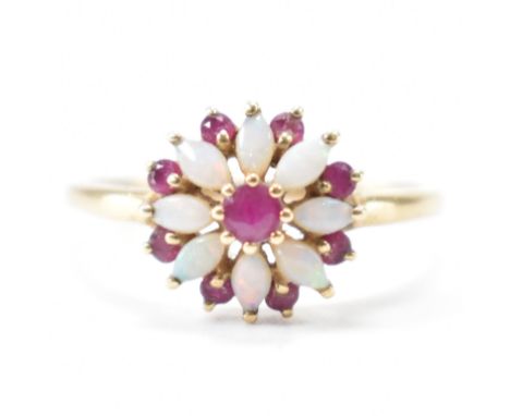 A hallmarked 9ct gold, ruby &amp; opal floral ring. The ring having a central round cut prong set ruby surrounded by petal li