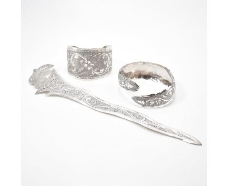 A group of Brunei South East Asian silver items. The lot to include two silver open cuff bangles with engraved floral detaili
