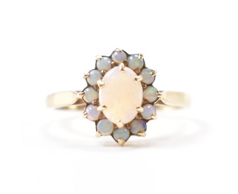 A hallmarked 9ct gold &amp; opal cluster ring. The ring having a central prong set oval opal cabochon surrounded by a halo of