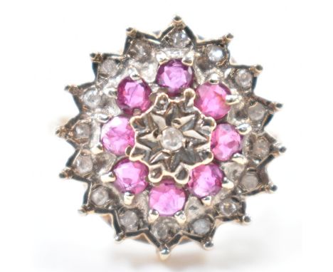 A hallmarked 9ct gold diamond &amp; ruby cluster ring. The ring having a a central round brilliant cut star set diamond, surr