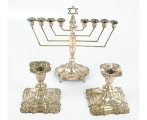 JOHN COLLARD VICKERY; a pair of George V hallmarked silver candlesticks with bell shaped sconces above shaped square stepped 