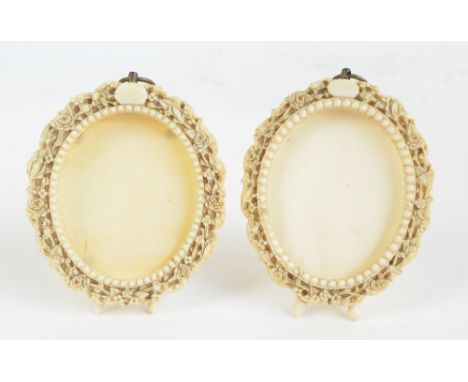 A pair of 19th century ivory oval photograph frames with bead decoration and finely carved floral border, with easel backs, a