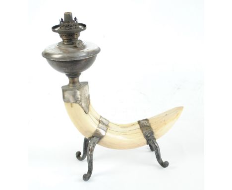 A late Victorian oil lamp with electroplated reservoir on mounted tusk base with four cabriole legs, height 41.5cm.