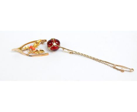 A 15ct yellow gold wishbone and holly bush leaf brooch set with two corals, registered number 136383, and a yellow mounted gl