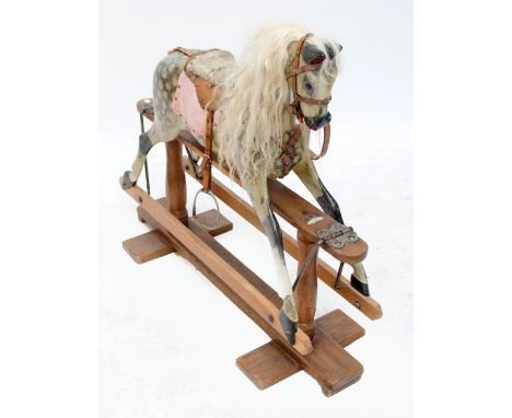 A Victorian dappled rocking horse of small dimensions with leather saddle and long blonde mane on trestle support bearing pla