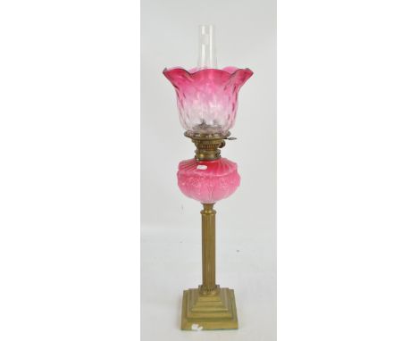 A late 19th century brass oil lamp with stepped square base, fluted column, pink glass reservoir and outswept fluted pink tin