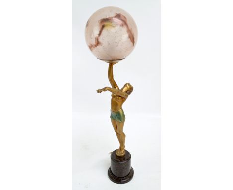 An Art Deco painted spelter figural lamp base modelled as a semi nude dancer holding a globular pale pink shade aloft, on cyl