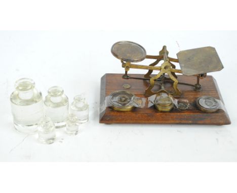 An early 20th century brass set of scales on oak rectangular base with set of stacking weights, 21.5 x 12cm, and a set of fiv