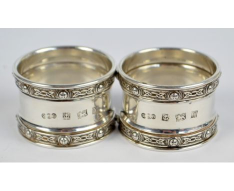 REID & SONS LTD; a pair of Elizabeth II hallmarked silver Celtic motif circular napkin rings, Birmingham 1972, diameter 4cm, 