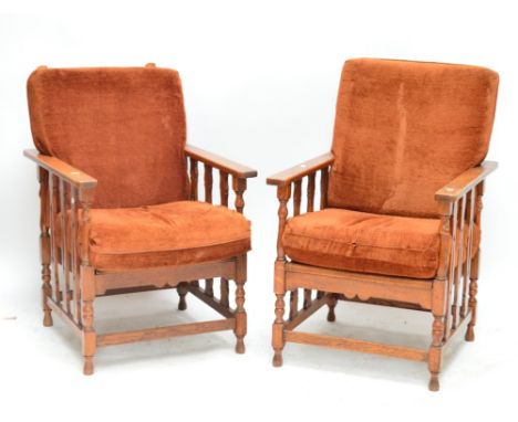 A pair of early 20th century oak framed Arts and Crafts reclining elbow chairs with pierced splats and bobbin and block turne