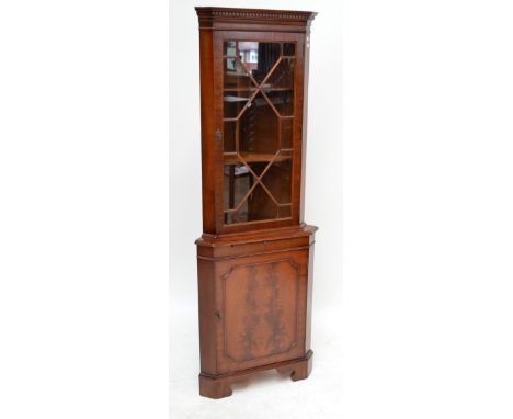 A reproduction freestanding corner cupboard with glazed upper section above single panel cupboard door enclosing single shelf