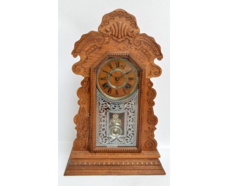 An American Ansonia chiming mantel clock with carved surround, decorated glass hinged door to the front, plinth below, the pa