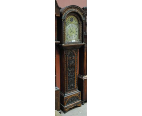 An early 19th century and later carved oak longcase clock with domed hood above arched brass dial with 'Old Father Time' abov