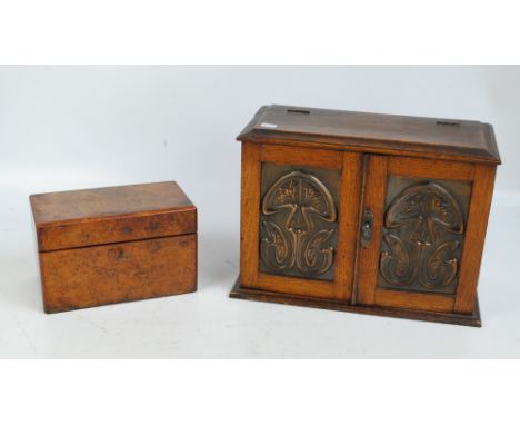 A small oak smoker's/games cupboard, the hinged doors with Art Nouveau metal panels with stylised floral motifs enclosing fit