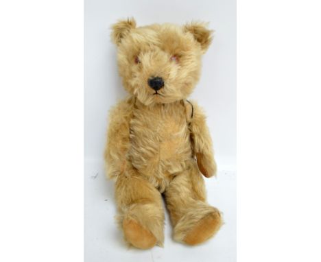 A Chiltern jointed musical clockwork teddy bear, the golden mohair body with central seam, orange and black glass eyes, plast