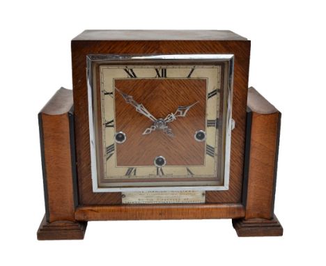 An Art Deco oak eight day chiming mantel clock, the square chapter ring set with Roman numerals, with presentation plaque 'Mi