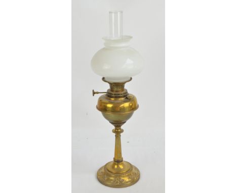 A 19th century brass oil lamp with circular base decorated with stylised motifs, brass reservoir with opaque white shade and 