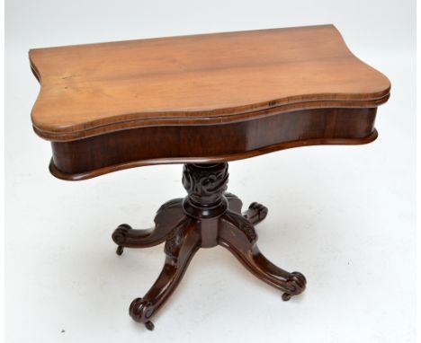 A Victorian walnut serpentine foldover card table with green baize inset top, on ring turned and foliate scroll carved column