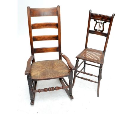 A 19th century ladder back, rush seated rocking elbow chair and an oak musical chair with lyre motif set into the back, cane 