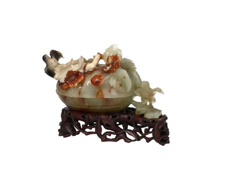 A multicolored jade carved in the shape of a box with a lid on a wooden base, with flowers, leaves and birds. Unmarked. China