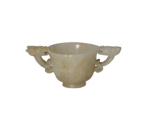 A cup carved from jade with a floral relief and two handles in the shape of mythical animals. Unmarked. China, 19th/20th cent