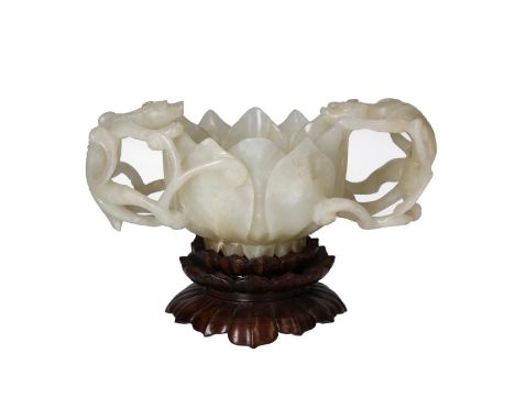 A jade cup in the shape of a lotus flower, with handles in the shape of chilong dragons. On wooden stand. China, 18th century