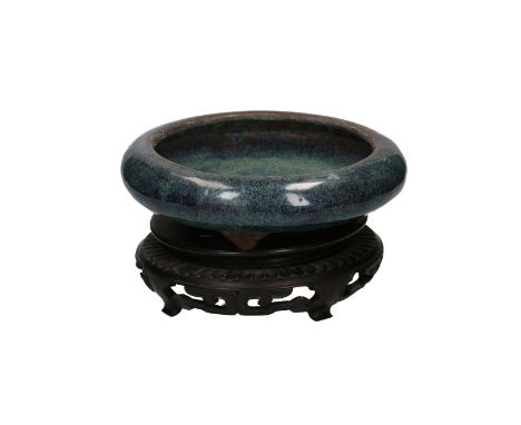 A blue glazed Yixing tripod bowl with speckles, on a carved wooden base. Marked with a seal mark, signed Ge Ming Xiang. China