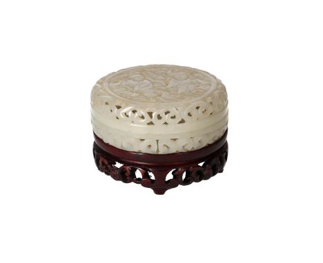 A round openwork jade lidded box, decorated with figures, on wooden base. China, 20th century.Diam. box 6 cm.Condition Report