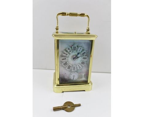 A CHIMING BRASS FRAMED CARRIAGE CLOCK with hinged handle, a landscape painted dial panel with Roman numerals, having repeater