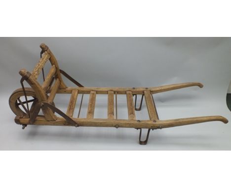 A 19TH CENTURY METAL FRAMED BREWER'S BARREL CADDY having slatted wood frame and single iron bound wheel, approx 190cm long 
