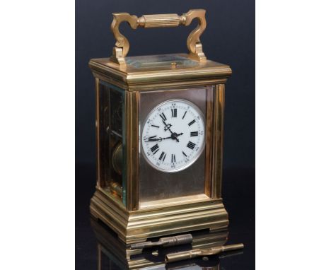 An antique French brass cased carriage clock with repeater movement and decorative white enamel dial. 