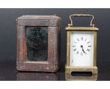 An antique brass carriage clock with white enamel dial complete with key and travel case. 