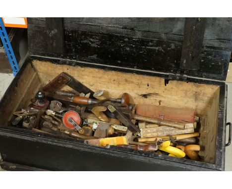 A wooden carpenters tool trunk complete with contents to include wood planes, braces, drills..etc. 