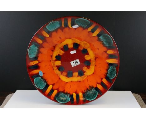 A Poole pottery 'Volcano' pattern charger decorated in orange, blue and green to red ground, measures approx 40cm in diameter