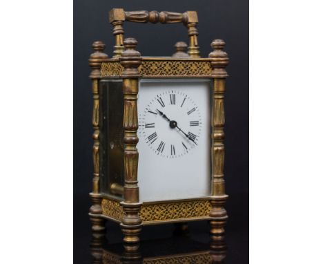 An antique brass cased carriage clock with ornate decoration and white enamel dial. 