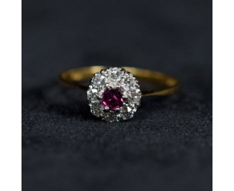 An 18ct gold ruby and diamond flower ring, centrally set with round free cut ruby with a surround of eight single cut diamond