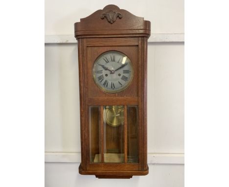 An oak cased mid century wall clock with bevelled glass windows. W:30cm x D:15cm x H:77cm