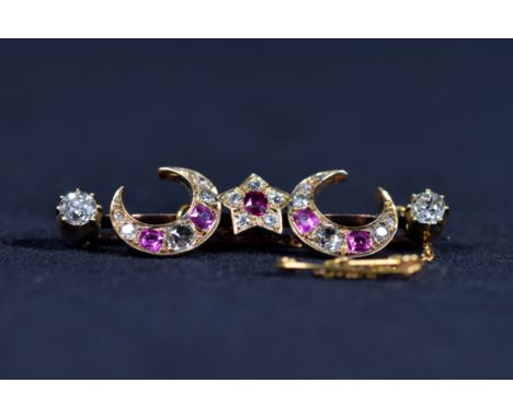 An unmarked precious yellow metal diamond and ruby bar brooch set with two 5mm old cut diamond finials and set throughout wit
