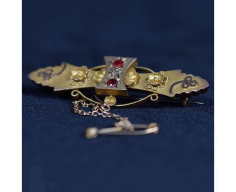 An Etruscan style 9ct bar brooch set with central rose cut diamond and ruby accents. 3.3g. 42mm.